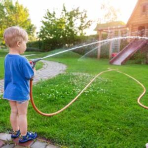 Boy holding hose horizontally for water limbo game