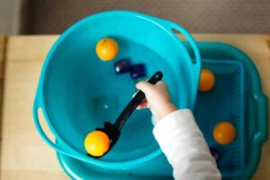 Boy playing with objects that float or sink in a bucket of water