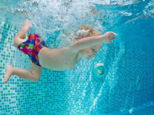 Boy swimming to bottom of pool to retrieve treasure