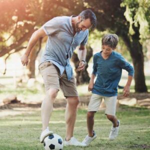 Father and son playing football in park