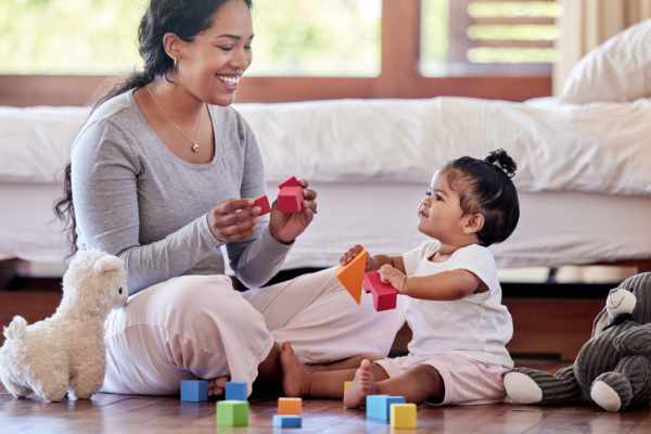 Mother and toddler sitting on floor playing