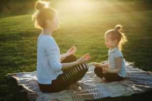 Mother and daughter enjoying quiet of yoga and meditation in the park