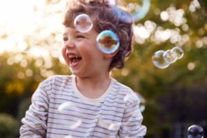 Toddler chasing and bursting bubbles outdoor