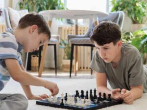 Two boys sitting on floor playing chess