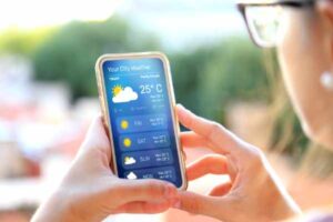 Woman outdoors, checking the weather forecast on her smartphone